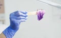 A girl beautician holds a sugar paste for epilation on a spatula under the light of a paw. Spatula and paste for hair removal in t