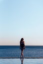 Girl in a beautiful bathing suit at sunset by the sea holding sunglasses