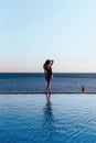 Girl in a beautiful bathing suit at sunset by the sea holding sunglasses