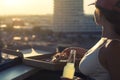 A girl with a beautiful breast in a sports suit holds pizza and drinks mojito on the sunset city background