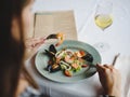A girl in a beautiful dress is eating a delicious seafood dish in a beautiful restaurant. Perfect time, tasty food. Royalty Free Stock Photo