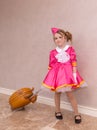 A girl in a beautiful fashionable dress with a child's suitcase.