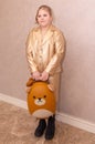 A girl in a beautiful fashionable dress with a child's suitcase.