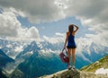A tanned young girl with long legs stands on top and looks at the snow-capped mountains Royalty Free Stock Photo