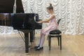 Girl in a beautiful pink dress playing on a black grand piano. Girl playing on a black piano. Royalty Free Stock Photo