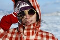 A girl with a beautiful radiant smile in sunny yellow glasses and red mittens is holding an icicle from Lake Baikal.