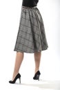 girl with beautiful slender legs in a long wool skirt on a white background, long gray plaid skirt Royalty Free Stock Photo