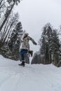 Women wearing warm down jacket walking in the wood at winter day. Female posing and dancing on snowy winter road Royalty Free Stock Photo