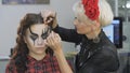 Easy Halloween Makeup. Girl in a beauty salon. Applying a stylistic pattern on the face of the model. The work of a master stylist