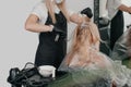 Girl in a beauty salon. A craftsman in black gloves smears paint on the hairs. hair dyeing services