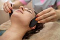 girl in a beauty salon doing a wonderful facial massage with stones to increase lymph flow. Royalty Free Stock Photo