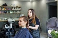 A girl in a beauty salon, a hairdresser does her hair, cuts her hair to a girl with long hair Royalty Free Stock Photo