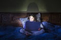 Girl in bed with laptop, glowing light.