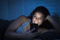 Girl in bed using mobile phone late at night at dark bedroom lying happy and relaxed Royalty Free Stock Photo