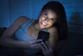 Girl in bed using mobile phone late at night at dark bedroom lying happy and relaxed Royalty Free Stock Photo
