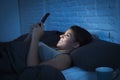 Girl in bed using mobile phone late at night at dark bedroom lying happy and relaxed Royalty Free Stock Photo