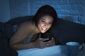 Girl in bed using mobile phone late at night at dark bedroom lying happy and relaxed Royalty Free Stock Photo