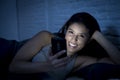 Girl in bed using mobile phone late at night at dark bedroom lying happy and relaxed Royalty Free Stock Photo