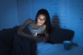 Girl in bed using mobile phone late at night at dark bedroom lying happy and relaxed