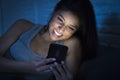 Girl in bed using mobile phone late at night at dark bedroom lying happy and relaxed Royalty Free Stock Photo