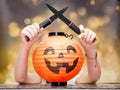 The girl behind the paper smiling pumpkin brandishes black knives tries to scare