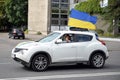 The girl behind the wheel of a car, to which a Ukrainian flag