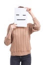 Girl covers her face with a smiley face sheet with a poker face on a white background