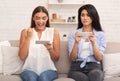 Girl being envious her friend`s victory in mobile game indoor