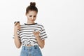 Girl being troubled checking schedule. Worried upset european woman with bun hairstyle in striped t-shirt, holding cup