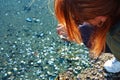 Girl bent over the beach collects shells in the sand Royalty Free Stock Photo