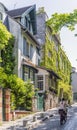 Girl on bicycle climbs up the cobblestone pavement of old Paris as she drives past green-filled houses Royalty Free Stock Photo