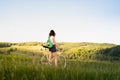 Girl with bicycle enjoying beautiful rural landscape. Young pretty female person with retro bike standing in a meadow on bright s Royalty Free Stock Photo