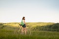 Girl with bicycle enjoying beautiful rural landscape. Young pretty female person with retro bike standing in a meadow on bright s Royalty Free Stock Photo