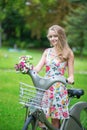 Girl with bicycle and flowers in countryside