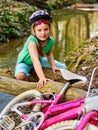 Girl on bicycle fording throught water onto log in park.