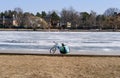 a girl with a bicycle sits with her back on the pier of a frozen lake Royalty Free Stock Photo