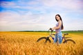 Girl with a bicycle on the wheat field