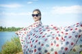 Girl with a big scarf on the beach. A girl holds a developing pareo scarf in the wind, standing by the river Royalty Free Stock Photo