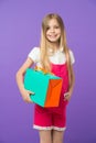 Girl with big smile holding colorful paper bag. Model with orange and green gift box. Child with long blond hair wearing Royalty Free Stock Photo