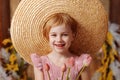 A girl in a big straw hat stands with a bouquet of flowers Royalty Free Stock Photo