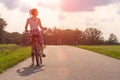 Girl with bike at the summer sunset on the road in the city park. Cycle closeup wheel on blurred summer background. Cycling down t Royalty Free Stock Photo