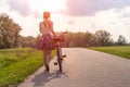 Girl with bike at the summer sunset on the road in the city park. Cycle closeup wheel on blurred summer background. Cycling down t Royalty Free Stock Photo