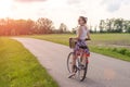 Girl with bike at the summer sunset on the road in the city park. Cycle closeup wheel on blurred summer background. Cycling down t