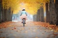 girl biking on a path with autumn leaves