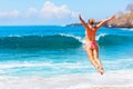 Girl in bikini jumping high on sea beach