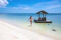 Girl in bikini running on sea water by white sand beach. Blue sea sky minimal landscape. South Asia or Bahamas island
