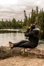 Girl with binocular sitting near Lake of two rivers in Algonquin National Park Canada Ontario natural pinetree landscape Royalty Free Stock Photo