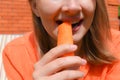 Girl bites raw carrot outdoor. Healthy raw food for health. Vegetarian concept