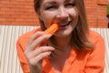 Girl bites raw carrot outdoor. Healthy raw food for health. Vegetarian concept