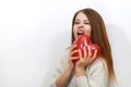 Girl bites a toy heart. Attractive young woman biting a red heart shaped balloon. Funny Valentines Day.